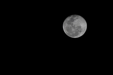 Close-up telephoto shot of a bright Full Moon isolated against a pitch-black sky. The image reveals sharp details of the lunar surface and craters, with ample space for text.