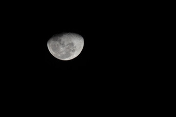 Obraz premium Close-up telephoto view of a Waxing Gibbous Moon isolated on a pitch black sky. The image shows sharp details of lunar craters and maria (seas).