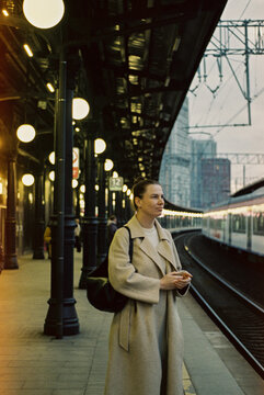 Woman waiting on a train platform during early evening  

