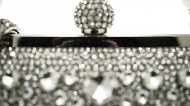 Close up of a sparkling crystal clutch purse with a jeweled clasp and metallic accents.