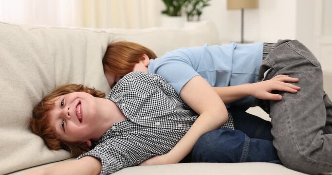 Two brothers fooling around on sofa at home