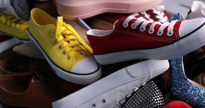 Pile of stylish shoes on grey floor, closeup. Camera moving left