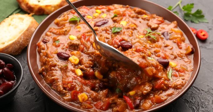 Woman eating chili con carne at black table, closeup