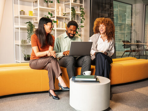Friendly Team Meeting On Yellow Couch With Laptop And Books 