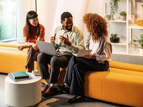 Collaborative Team Meeting in Modern Office Lounge With Laptop