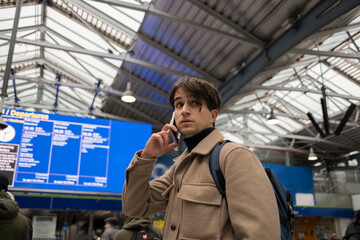Young Man Travels While Checking Train Schedules and Chatting