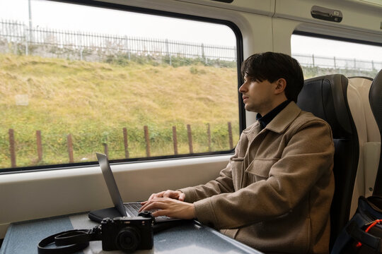 Young Man Working on Laptop While Commuting on Train