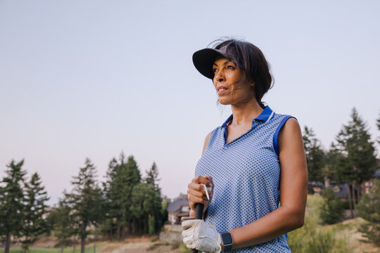 Candid outdoor golfer woman holding a golf club, smiling