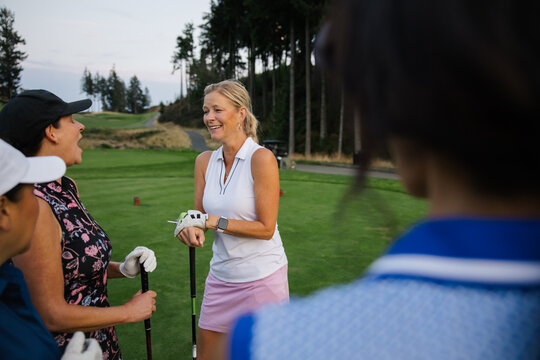 Candid moment on the golf course: friends chatting and smiling
