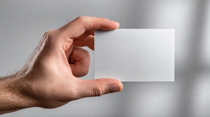Fototapeta premium Closeup of Hand Holding Blank Card for Presentation or Display in Neutral Background