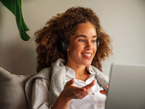 Happy Woman with Curly Hear Using Headphones and Laptop 