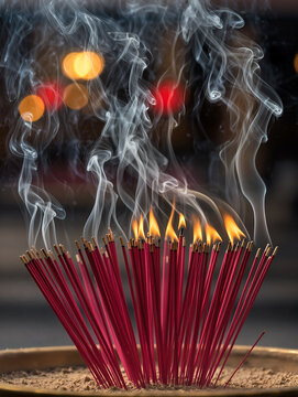 Close up burning of  dozens red incense sticks with rising smoke