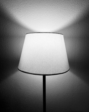 velador de pie prendido contra una pared en blanco y negro