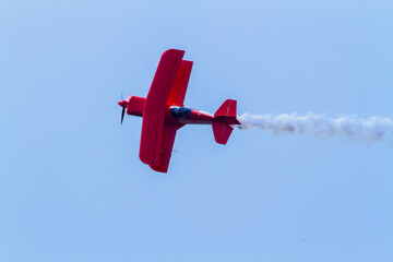 red biplane in flight trailing smoke © ken duffney