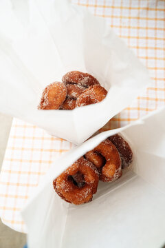 Delicious Freshly Made Donuts in Paper Bags on a Checkered Table