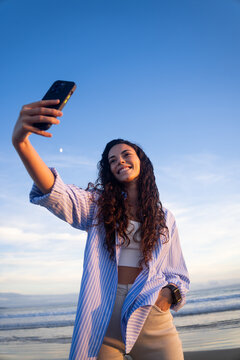 Woman takes a selfie at the beach, blue sky