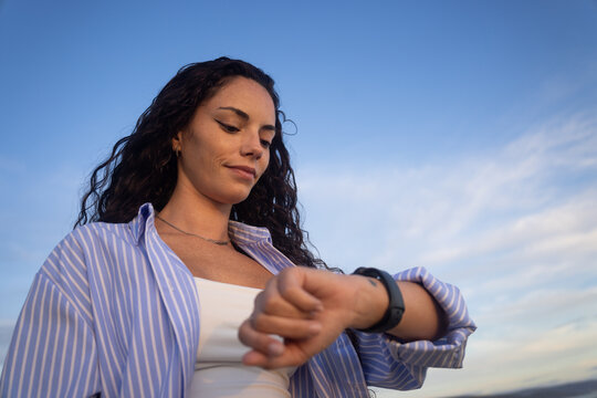 Woman Checking Watch Against a Clear Blue Sky, low angle
