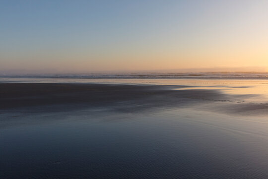 Expansive beach at sunset, tide pools in foreground