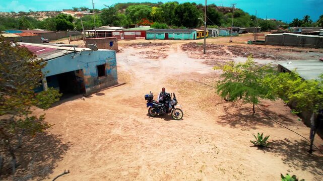 Aerial view of a person on a motorcycle in dry village landscape