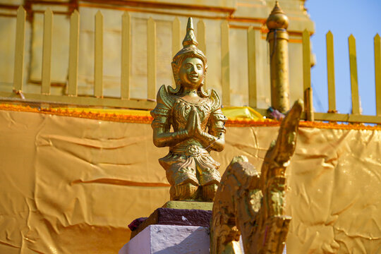 Traditional golden Thepanom angel statue in praying gesture at Wat Phra That Doi Kham temple on the mountain side of Chiang Mai, Northern Thailand