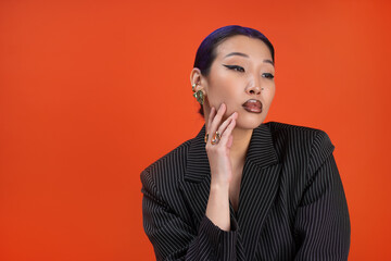 Stylish woman with trendy rings on vibrant orange background