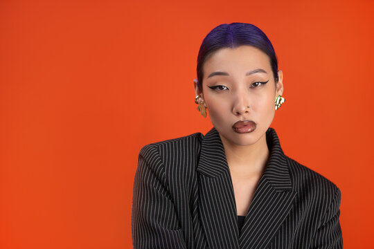 Stylish woman with trendy makeup on vibrant orange background