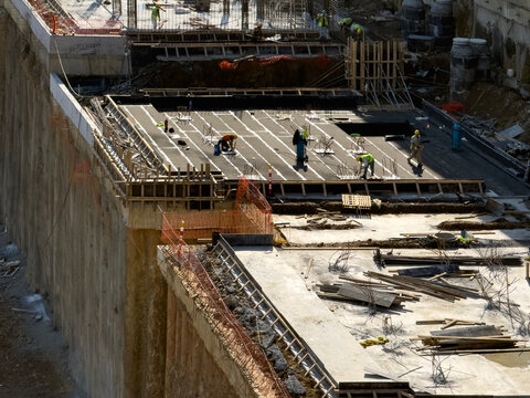 Construction site workers on a large, high concrete foundation