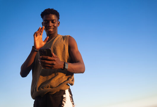 Young Man Waves at smartphone 