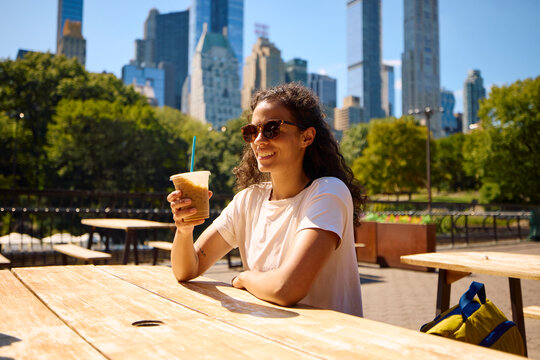 Smiling woman drinks coffee in Central Park