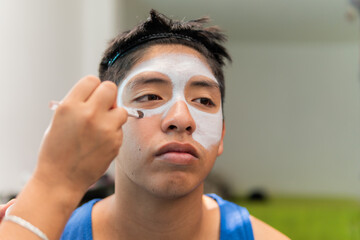 Young man getting dia de muertos makeup applied