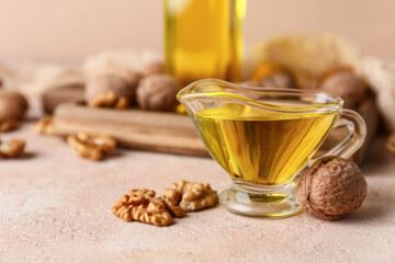 Gravy boat of fresh walnut oil and nuts on beige background