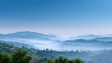 Serene Misty Mountainscape with Layered Hills Under a Clear Blue Sky Illuminated by Soft Morning Light