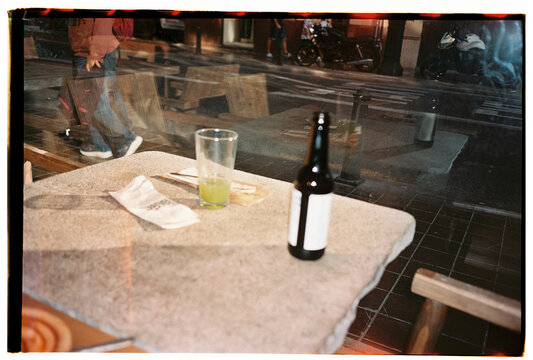 Reflected street view through caf&eacute; window with bottle and glass