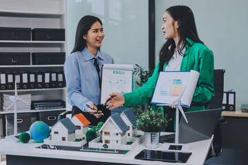 Hands of adult Asian business professionals analyzing ESG financial data and renewable energy project plans