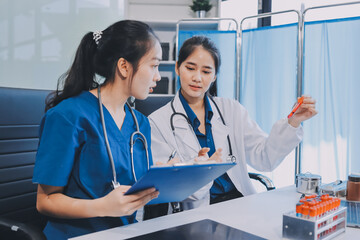 Medical team meeting analyzing blood test results in hospital laboratory. Doctors and scientists in lab coats are having a discussion about blood test result, holding test tubes and taking notes.