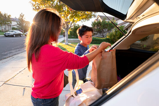 family unloading groceries car trunk