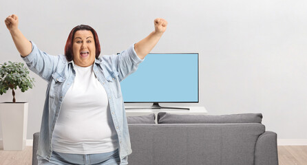 Excited plus-size woman cheering in front of TV