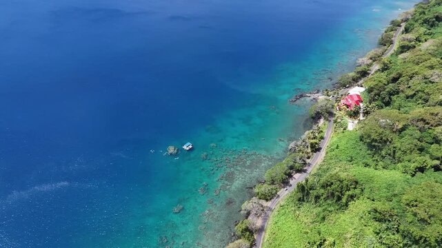 High-angle drone perspective of the rugged and pristine volcanic coastline of Samoa, featuring verdant mountainsides and the expansive blue Pacific Ocean.
