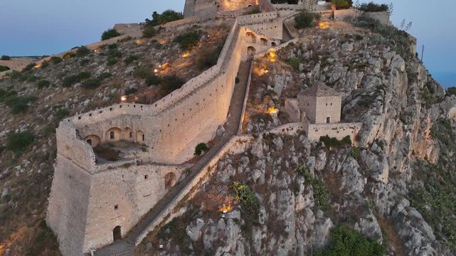 Peloponnese,Nafplion,Aerial view tilt up slowly from low angle of the beautifully illuminated Palamidi Fortress during sunset. Low angle covering all fortress in one screen at the end.