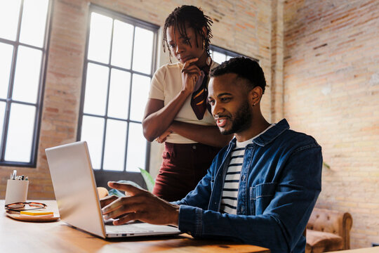 Coworkers collaborating on laptop in modern office