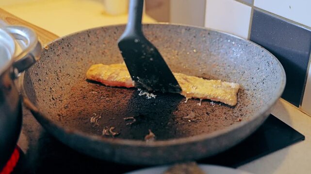 Fresh cod fillet placed on pan during home cooking scene for healthy lifestyle