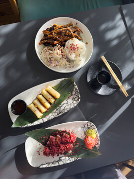 Sushi, spring rolls and asian food on a dark gray table