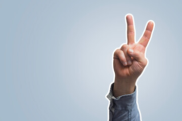 Human hand in a denim shirt, showing the universal gesture of victory or peace. The index and...