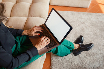 Crop of anonymous woman using laptop at home