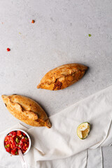 Overhead view of baked empanadas with pico de gallo on a grey cement countertop, top view of empanadas and salsa, bolivian salte&ntilde;a with chopped tomato sauce
