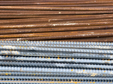 Close-up texture of new and rusty stacked steel rebar rods