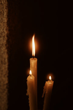 Soft Glow From Three Burning Candles in Dark Setting