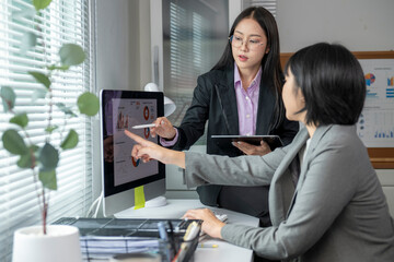Businesswomen analyzing financial charts on computer in office