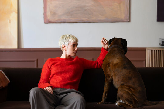 Woman With Short Blonde Hair In Red Sweater Interacting With Dog
