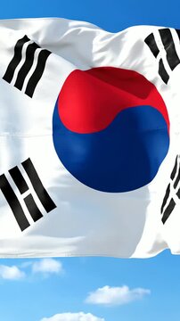 澄み切った青空と白い雲を背景に、風になびく韓国の国旗